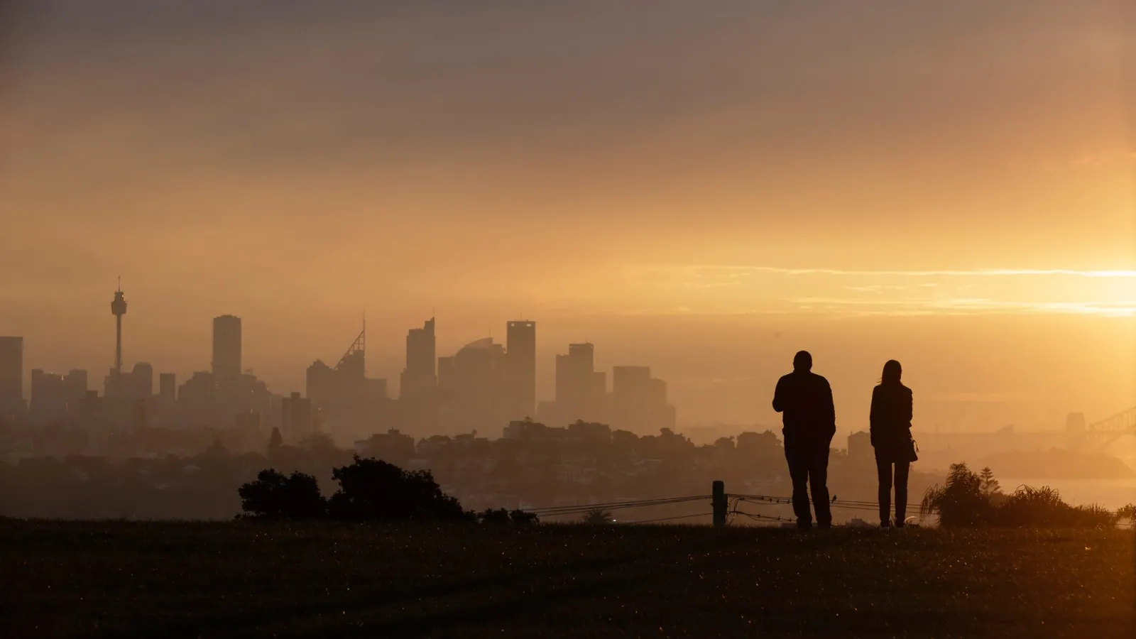 Two figures overlooking a cityscape that has poor visibility