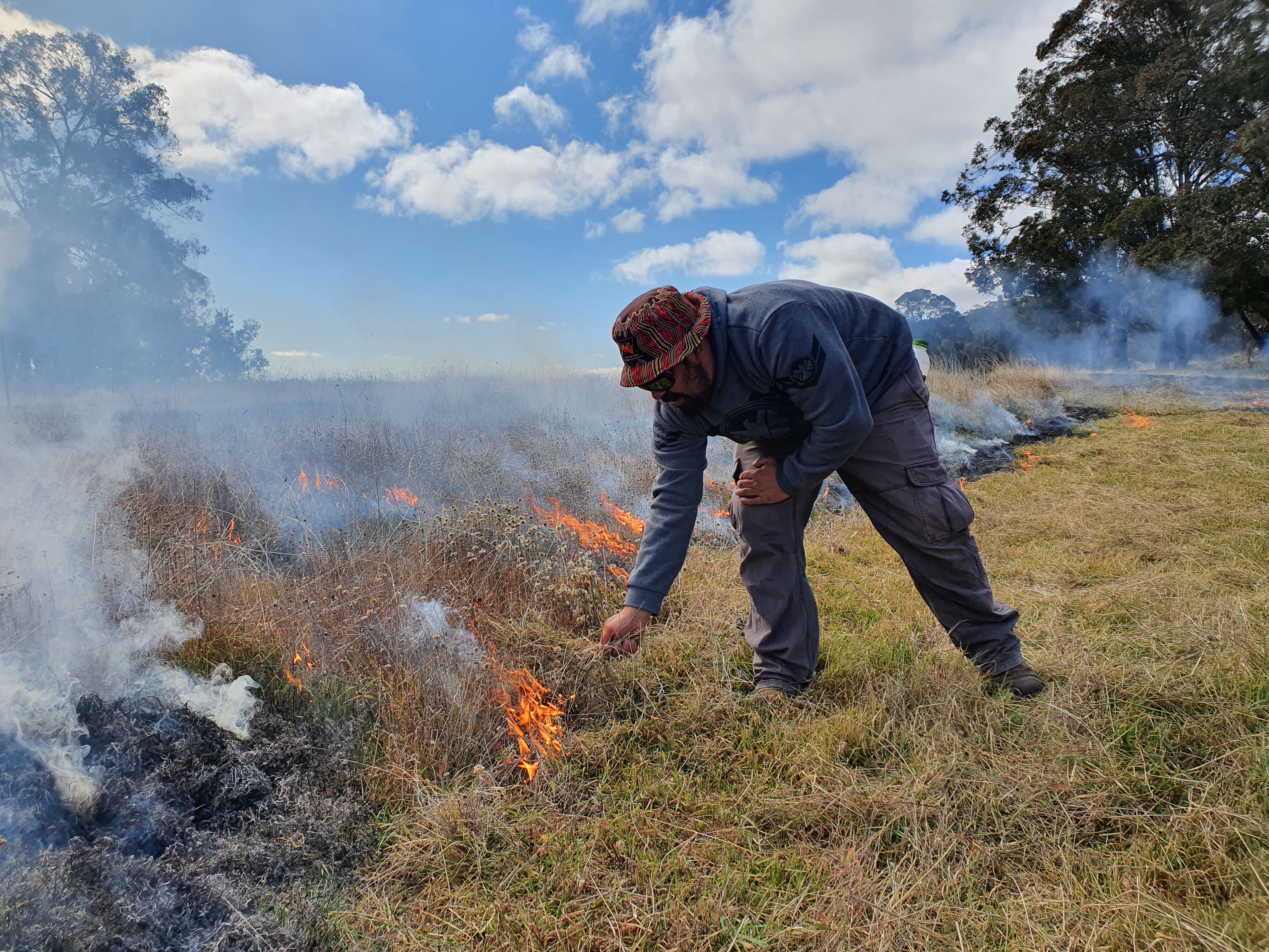 A ranger setting low growth on fire.